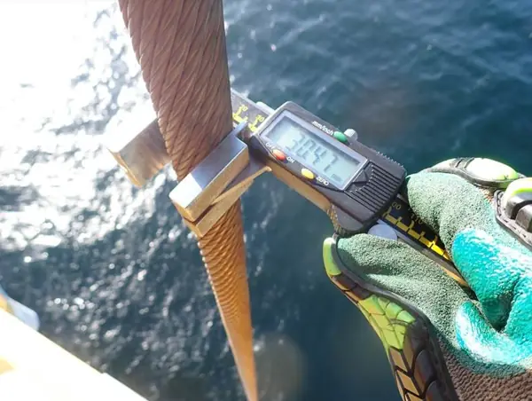 Digital caliper measuring the diameter of an offshore crane hoist rope above the sea