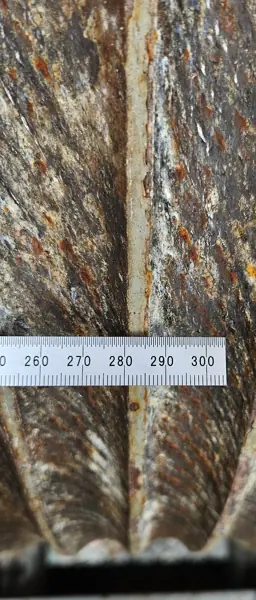 Ruler across rusty hoist drum grooves on a Potain MR 615 to measure groove pitch