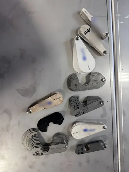 Steel and plastic sheave gauges of different designs and shapes laid out on a bench