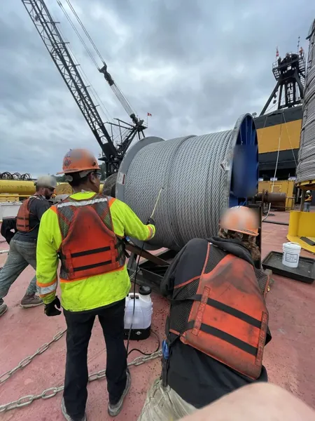 Crew lubricating a reel of boom hoist rope on a Clyde 700 t floating crane