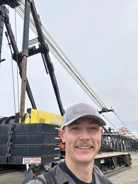 Dean McDonald in front of a Manitowoc 2250 crawler crane during a boom hoist rope inspection