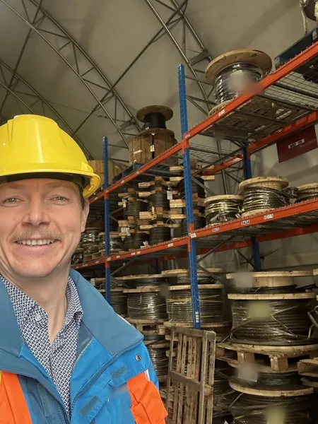 Dean McDonald in a port's rope store, in front of reels of spare crane ropes he supplied